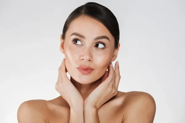 Mujer mostrando su cara brillante tras tratamiento de pink glow y limpieza facial.